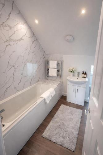 a white bathroom with a tub and a sink at The Miles Arms Hotel in Avonmouth