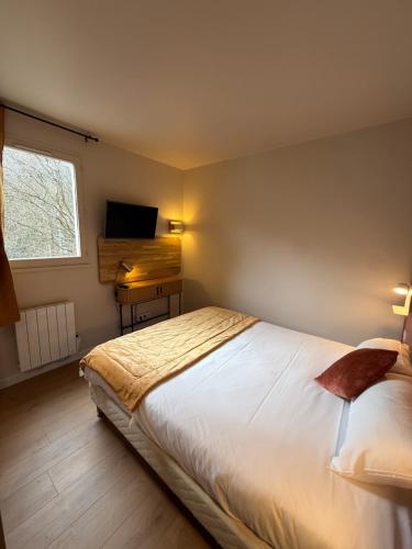 a bedroom with a bed and a desk and a television at Logis Hôtel La Cascade - Lyon Nord in Saint-Genis-les-Ollières