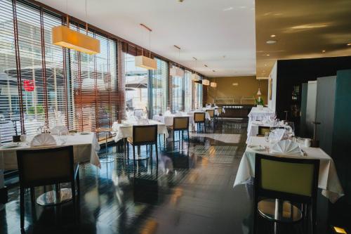 a restaurant with white tables and chairs and large windows at Quinta Mirabela - Design Hotel in Funchal