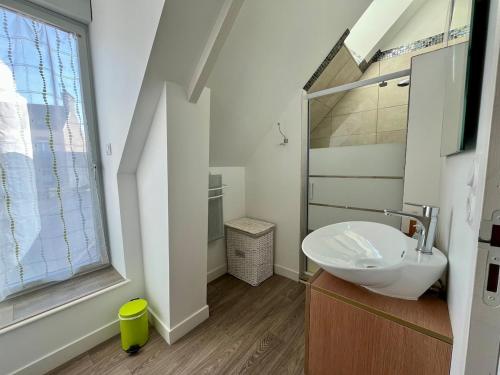 a white bathroom with a sink and a window at L'Erable - Maison vue mer in Donville-les-Bains