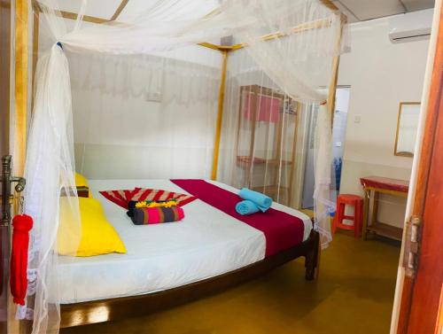 a bedroom with a canopy bed with colorful pillows at Dream Haven Mirissa in Mirissa