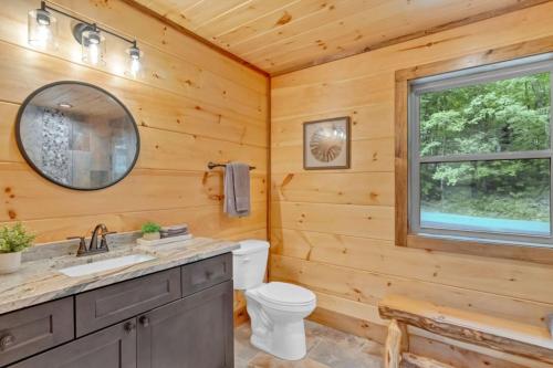 a log cabin bathroom with a toilet and a window at Sneaky Bear in Sevierville