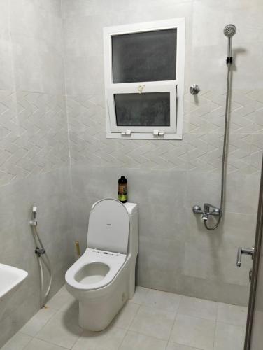 een badkamer met een toilet met raam en een wastafel bij Ocean Hostel in Seeb