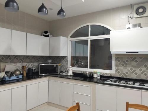 een keuken met witte kasten en een raam bij Ocean Hostel in Seeb