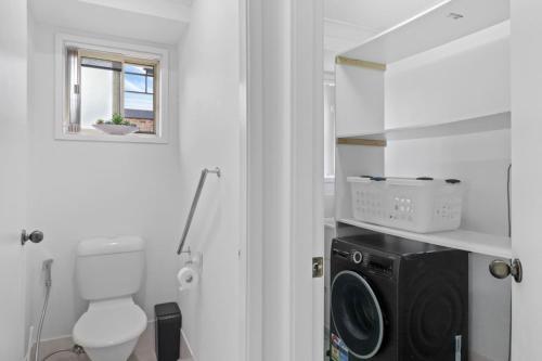 a bathroom with a toilet and a washing machine at Wangi Waters and Views in Wangi Wangi