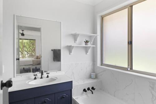 a white bathroom with a sink and a mirror at Play and Pool Bonnells Bay in Bonnells Bay