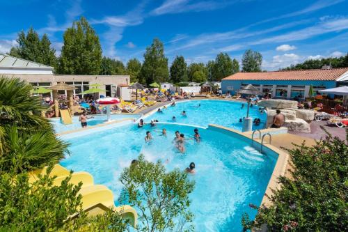 a group of people in a swimming pool at a resort at Camping Le Bois Soleil - Mobil home 3 pièces 4 personnes + TV MAE-4364 in Les Sables-d'Olonne