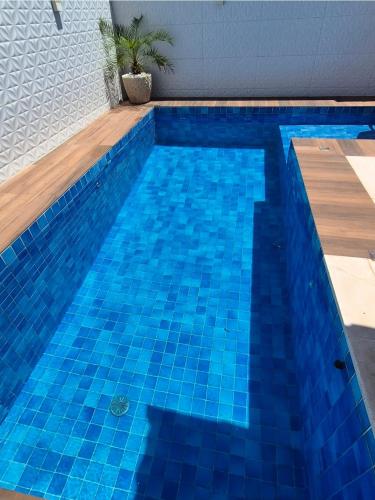 a blue tile swimming pool with a wooden deck at Casa piscina privativa e Área Gourmet - Condomínio 24 hs in Araruama