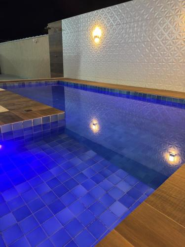 a swimming pool with blue tiled floors and lights at Casa piscina privativa e Área Gourmet - Condomínio 24 hs in Araruama