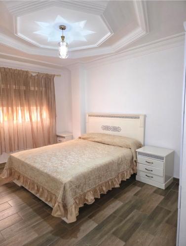 a bedroom with a bed and a chandelier at إقامة الكرنيش in Nador