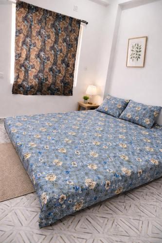 a bedroom with a large bed with a blue blanket at Laxmi Narasimha homestay in mayapur