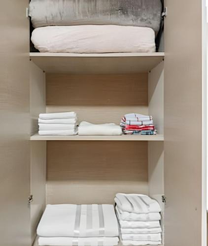 a closet with white towels and a bed at Alto padrão, 2 suítes e lazer privativo in Joinville