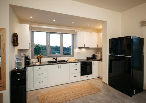 a kitchen with white cabinets and a black refrigerator at Irini's Beach House in Ambrami