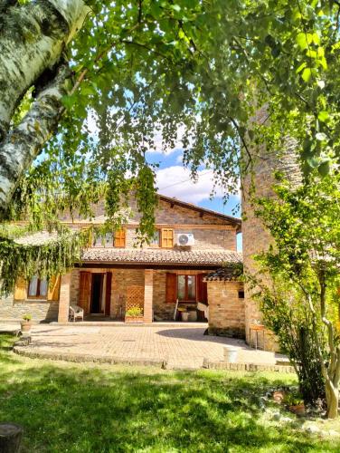 an exterior view of a stone house with a tree at Villa Montegenco B&B in Comunanza
