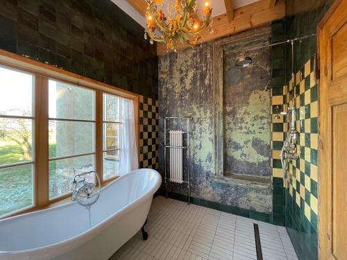 a bathroom with a tub and a window and a chandelier at Der Schwan - Gutshaus Bückling in Rambin