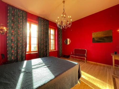 a red bedroom with a bed and a chandelier at Der Schwan - Gutshaus Bückling in Rambin