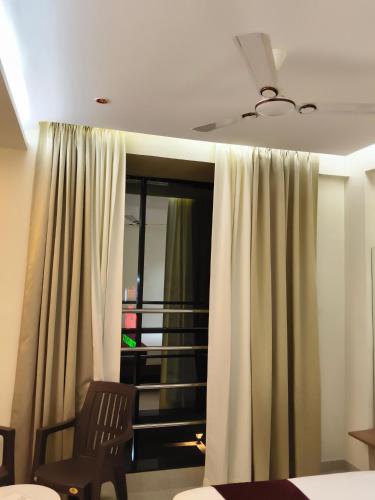 a room with a bed and a window with curtains at Hotel Atithi Lodging Pune in Pune