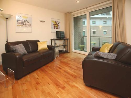 a living room with a leather couch and a television at Marina Secret - on Poole Quay with Free Parking in Poole