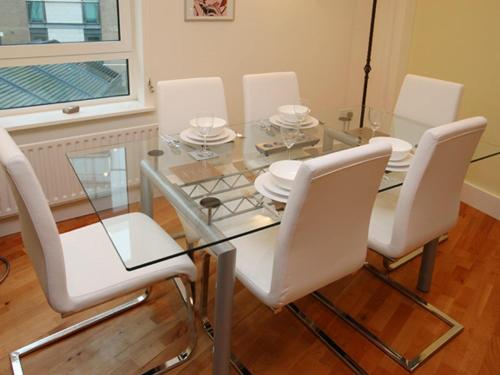a dining room with a glass table and white chairs at Marina Secret - on Poole Quay with Free Parking in Poole