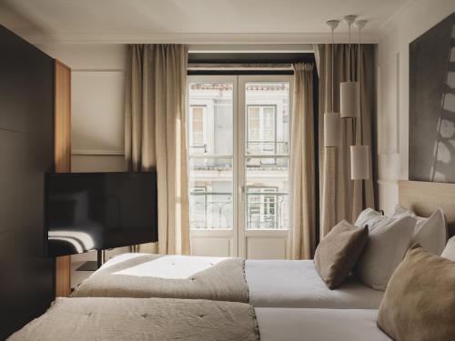 a hotel room with two beds and a television at Casa Solayme Garrett in Lisbon