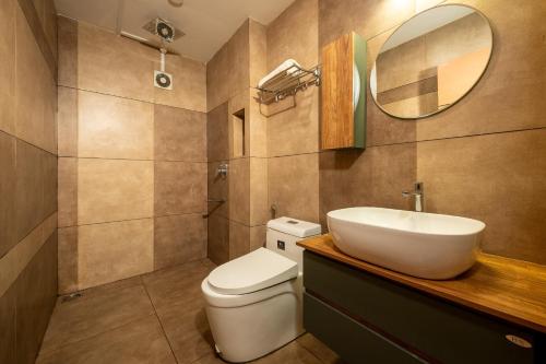 a bathroom with a toilet and a sink and a mirror at Monsoon Retreats by DAAN in Thekkady