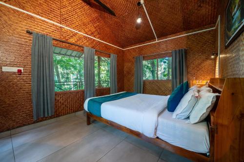 a bedroom with a bed and a large window at Monsoon Retreats by DAAN in Thekkady