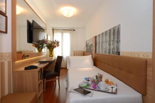 a hotel room with a tray of food on a bed at UNAHOTELS Ala Venezia-Adults 16 in Venice