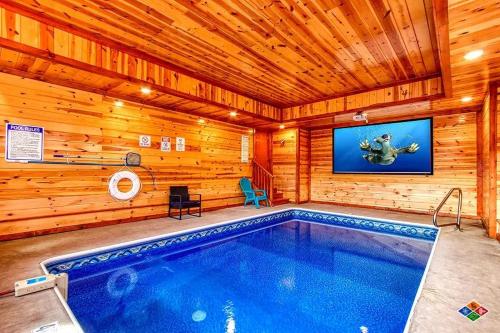 a swimming pool in a wooden house with a tv at Paradise Pointe Pool Lodge by Beyond Expectations in Sevierville