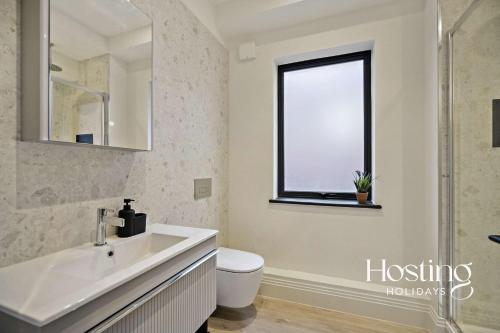 a bathroom with a sink and a toilet and a window at Platform One Apartments - Caversham in Reading