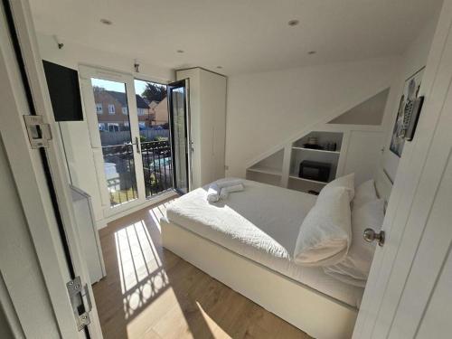 a white bedroom with a bed and a large window at Albion's House in Luton