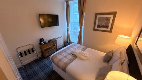 a bedroom with a bed and a tv on the wall at The Waverley Guest House in Inverness