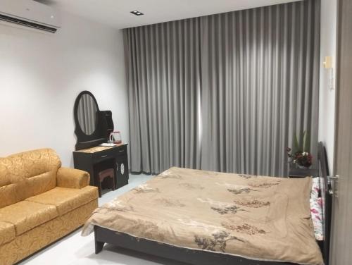 een slaapkamer met een bed, een bank en een spiegel bij Ocean Hostel in Seeb