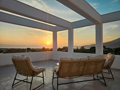 a patio with a couch and chairs and a sunset at Areti White Villas in Loutraki