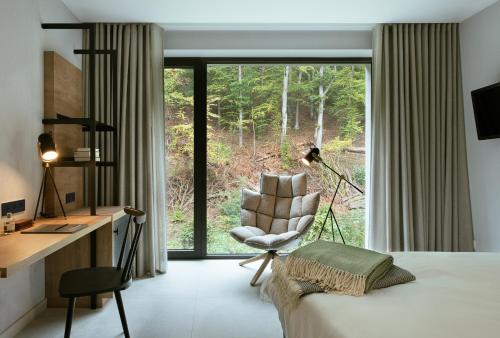 a bedroom with a desk and a chair in front of a window at Hotel VierJahreszeiten am Seilersee in Iserlohn