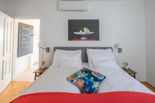 a bedroom with a white bed with a red blanket at Gut Purbach in Purbach am Neusiedlersee