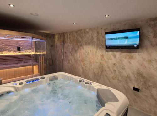 a large bath tub with a tv on a wall at Belajec Wine & Nature Retreat in Veliko Brdo