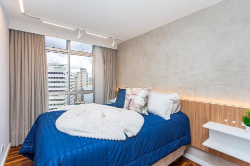 a bedroom with a blue bed and a window at Galeria Tijucas in Curitiba