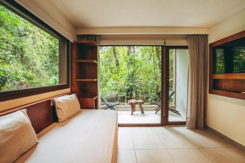 a bedroom with a bed and a large window at Hotel Tré Iguazú in Puerto Iguazú