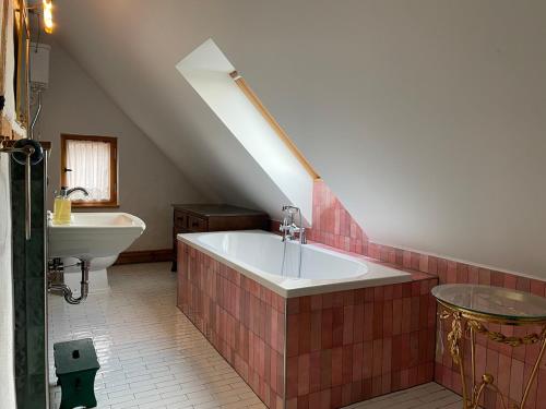 a attic bathroom with a tub and a sink at Die Perle - Gutshaus Bückling in Rambin