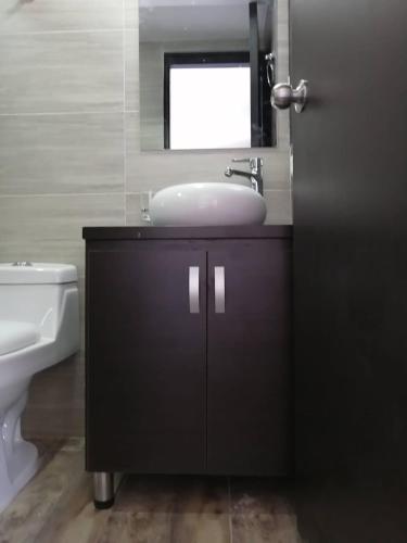 a bathroom with a sink and a mirror and a toilet at HOTEL El MONARCA in Tunja