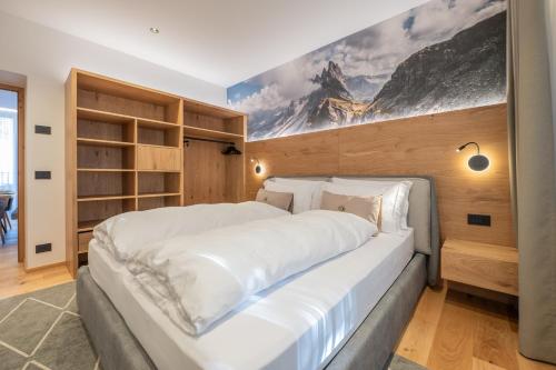 a bedroom with a large white bed with a painting on the wall at Appartament Seceda in San Sigismondo