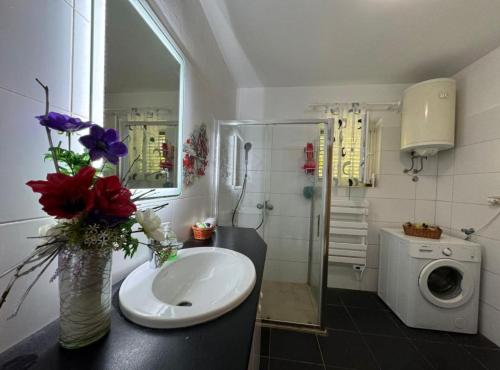 a bathroom with a sink and a vase of flowers at Family Apartment Sofija in Preko