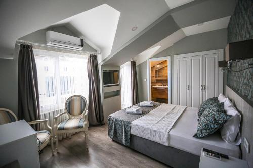 a bedroom with a bed and a chair and a window at Doa Suite Hotel in Trabzon
