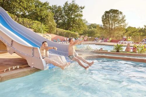 two young boys sliding down a slide in a swimming pool at ZEcamping 4 étoiles familial avec piscine couverte in Laroque-des-Albères