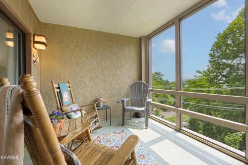 a room with a balcony with chairs and windows at Misty Mountain Condo by Beyond Expectations- 3BR Retreat with Scenic Views, Sleeps 8 & Near Ober Mountain in Gatlinburg
