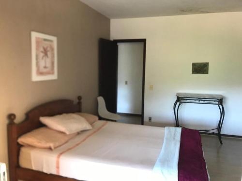a bedroom with a bed and a table in it at Casa Compartilhada na CBF, granja comary in Teresópolis
