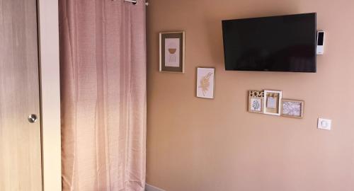 a room with a television on a wall with pictures at Chambre la Bohème in Élancourt