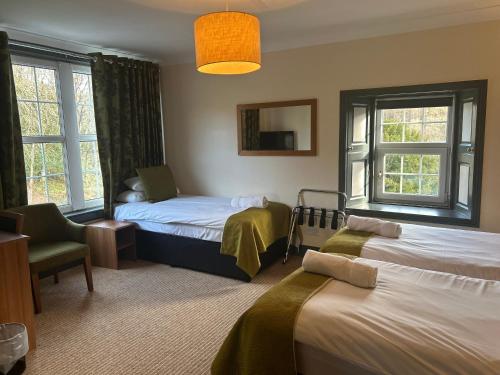 a room with two beds and a chair and windows at Rowardennan Hotel in Rowardennan
