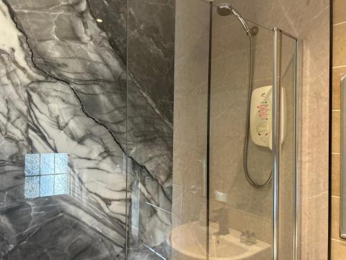 a shower with a glass door next to a sink at Rowardennan Hotel in Rowardennan