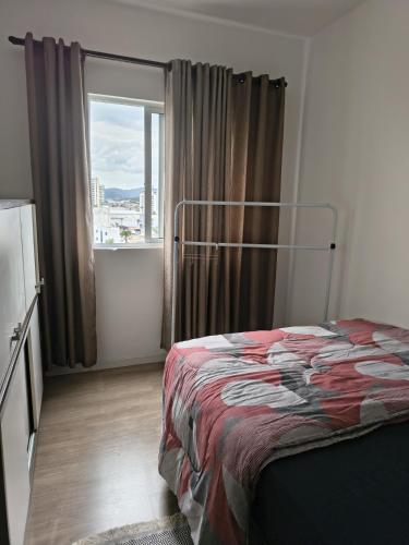 a bedroom with a bed and a large window at Casa Rebello - Pousada in Itajaí